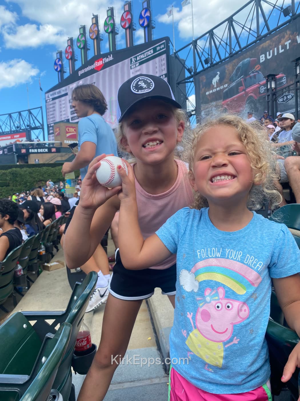 Kirk's daughters showing off a baseball at a game